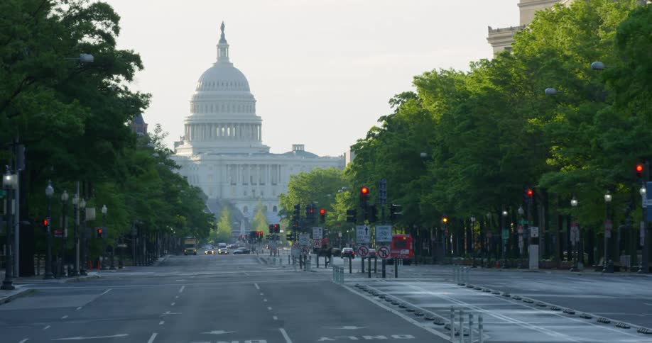 An intersection of wide streets lined with trees and leading to a government building