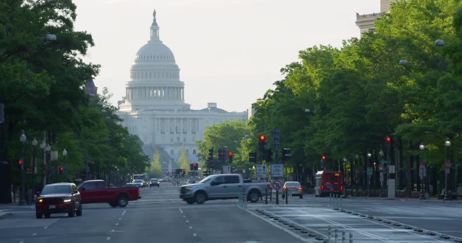 A city street with vehicles and the united states capitol building in the background