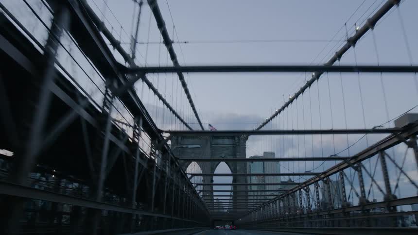 Vehicles head toward downtown on a suspension bridge at dusk