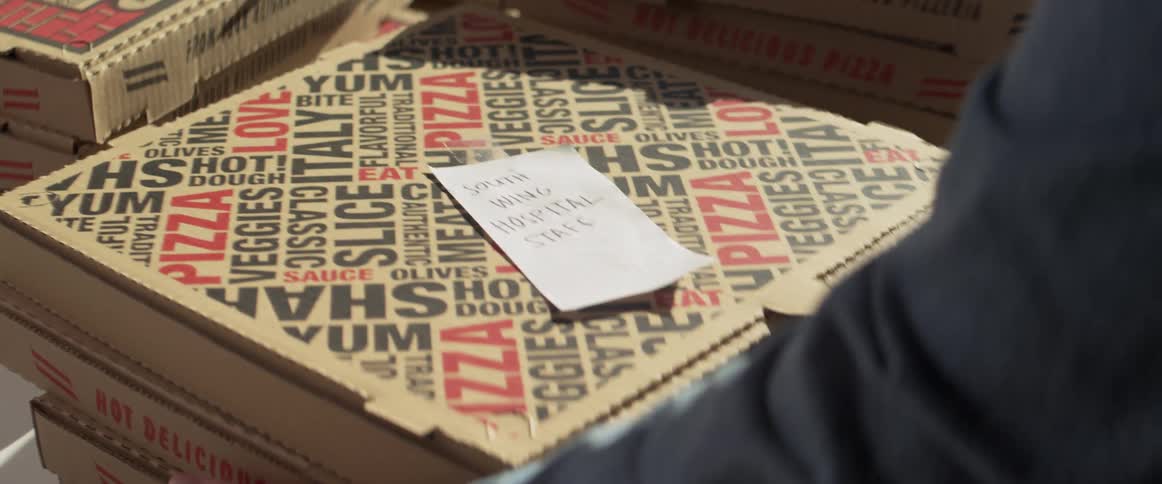 A man puts a note on a stack of pizzas and picks them up