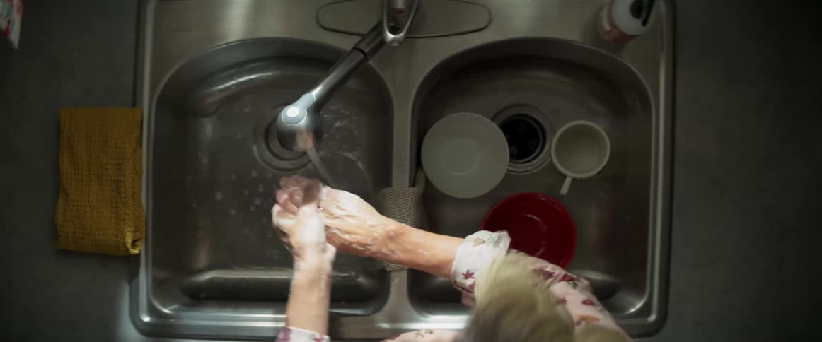 Woman washing hands at the kitchen sink