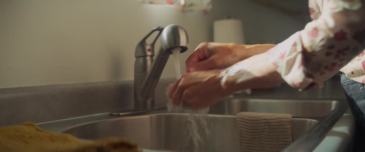 A woman is washing her hands in the sink