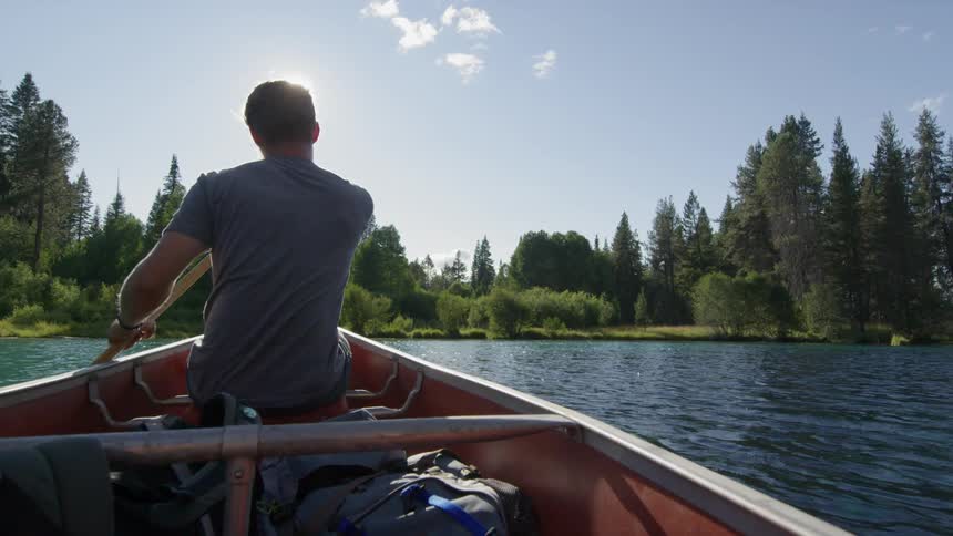 A man paddles a kayak through clear water on a sunny day