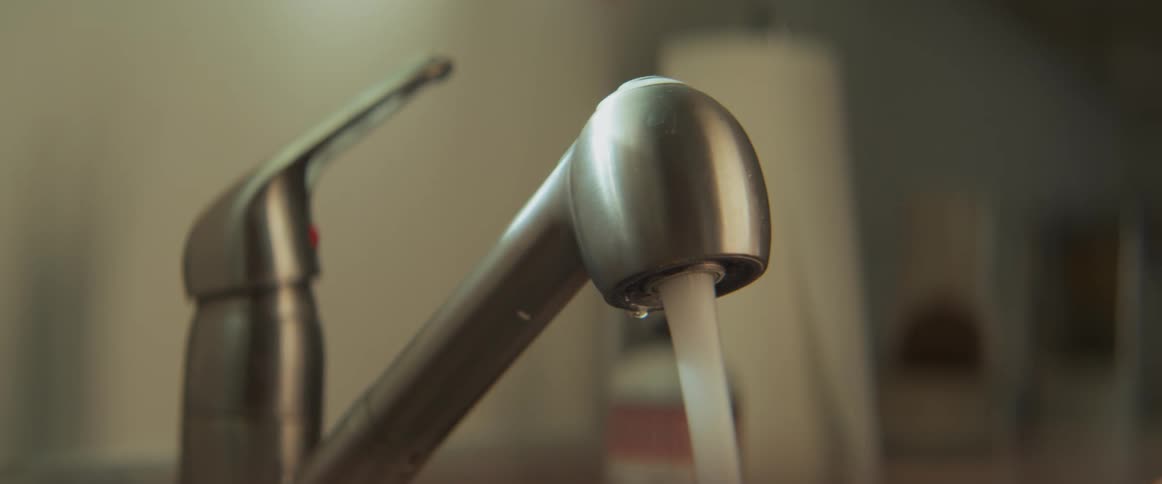 A persons hand putting on and turning off a water faucet