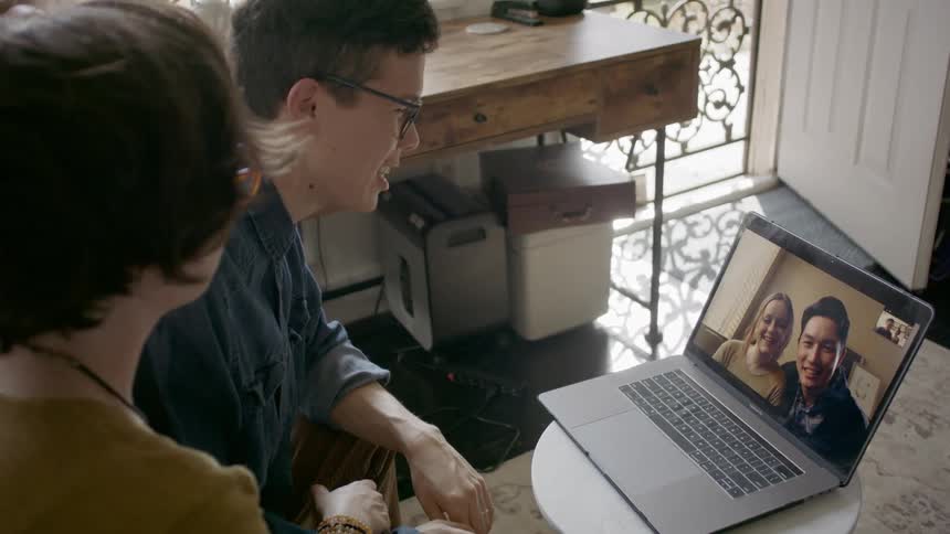 A man and a woman video chatting with another man and a woman on a laptop