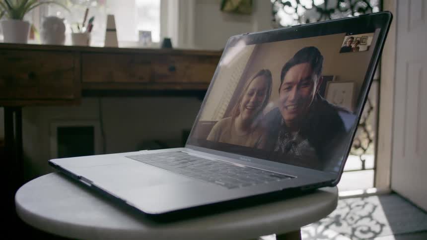 Couple makes a video call on the laptop with their friends in the living room