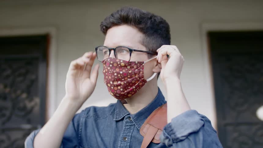 Man wears a patterned face mask and walks out of the house