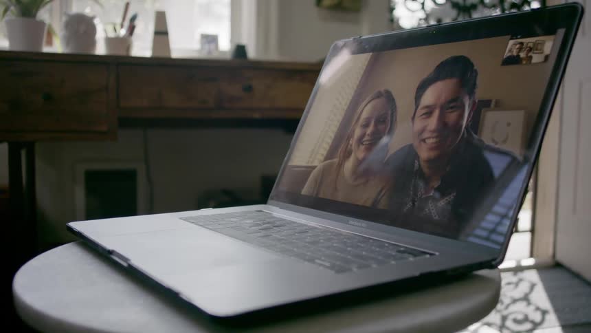 A couple chats with another couple via video call on a laptop
