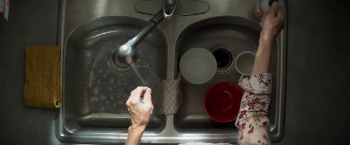 Woman washes hands with liquid soap on the kitchen sink