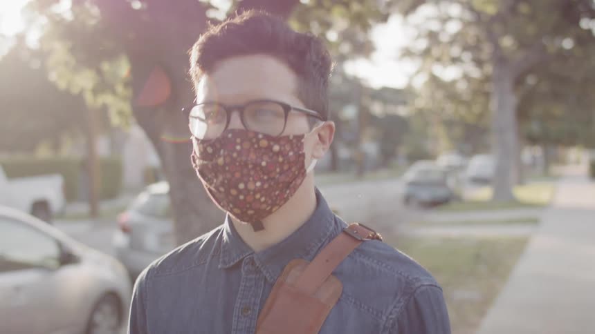 A teenager wearing a mask walks down the street