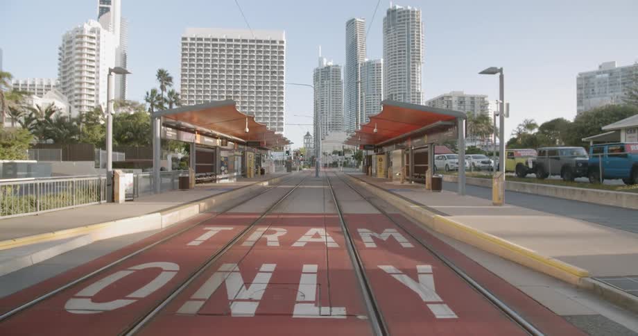 Cars parked on a street next to train tracks at a station