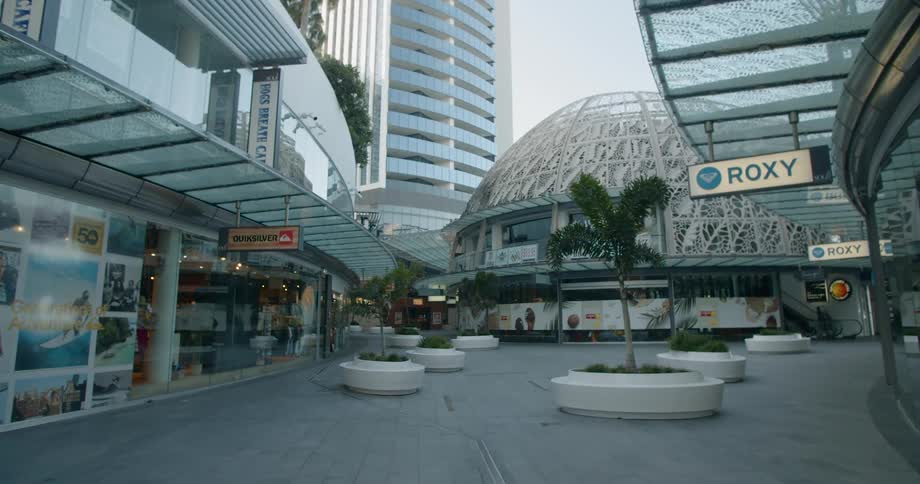 Palm trees and concrete seating fill the walkway between shops and restaurants