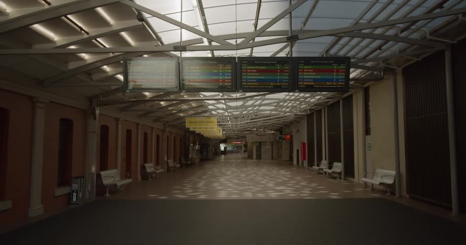 Monitors hanging from a glass ceiling in an empty corridor