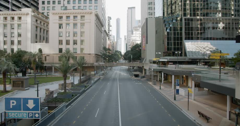 An empty city road with buildings trees and signs