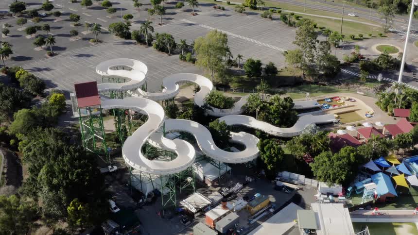 A water park with a large curved slide is empty at midday