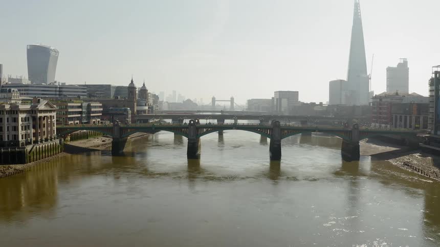 A truck drives across a bridge with the city skyline in the distance