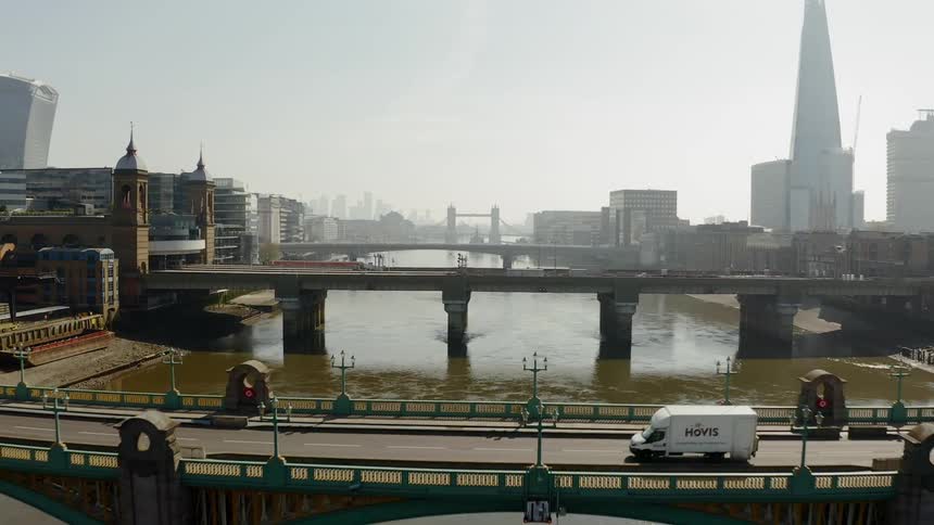 A van travels a large city bridge over a muddy river