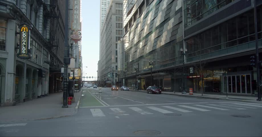 A couple vehicles drive down an empty city street