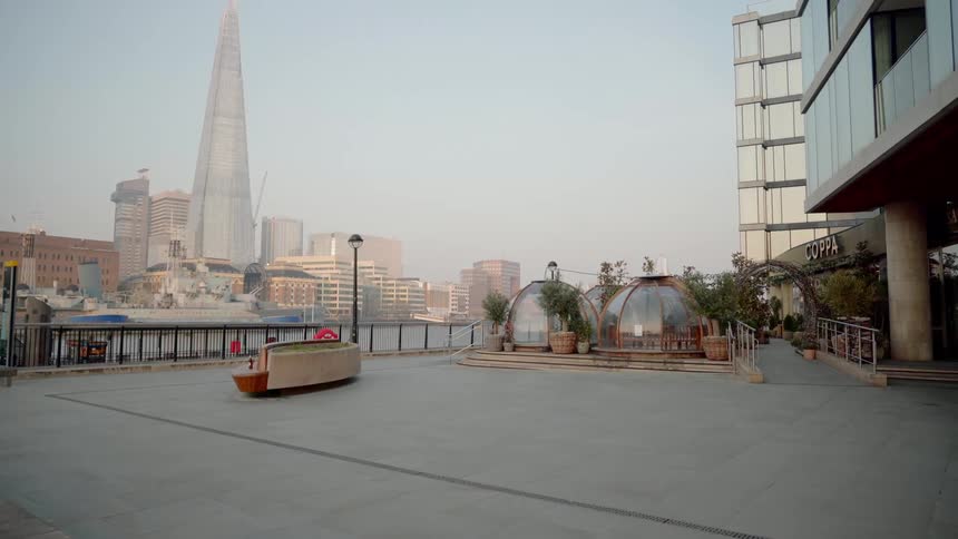 A boardwalk near a river with buildings and skyscrapers in the background