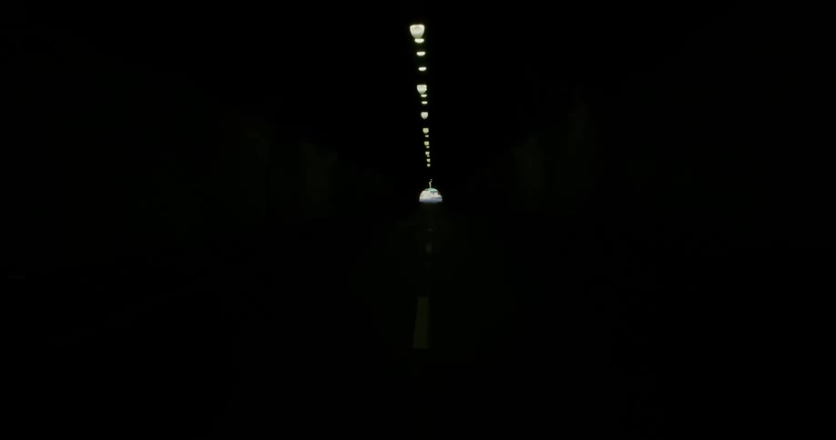 A tunnel with a road and lights above