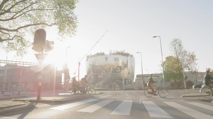 Cyclists and automobiles crossing a wide street at an intersection in a city