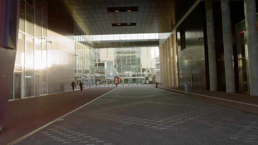 People walking along a walkway through a passage under a building
