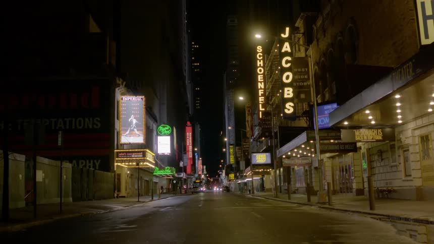 Police lights flash at the end of an empty street of businesses