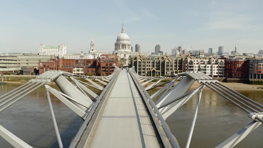 A woman walks across a pedestrian bridge that leads to downtown