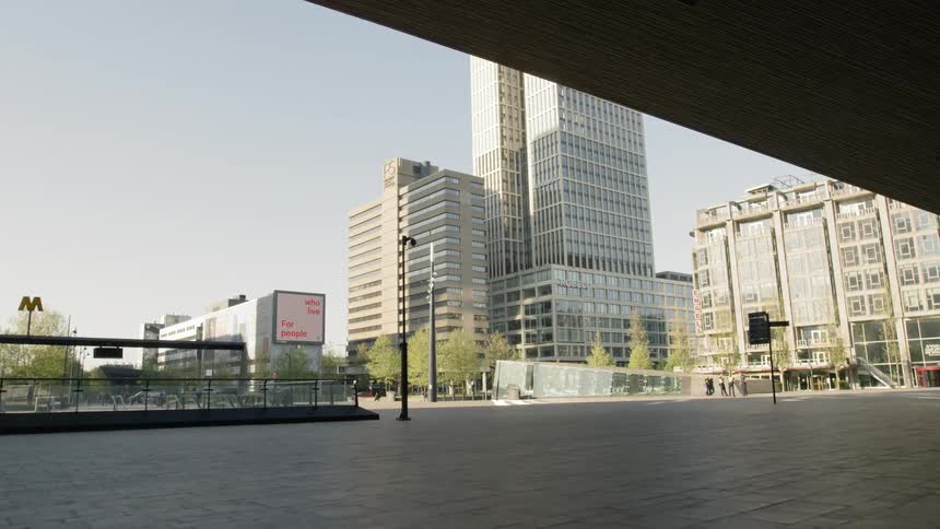 Video plays on screen on side of building next to twin skyscrapers