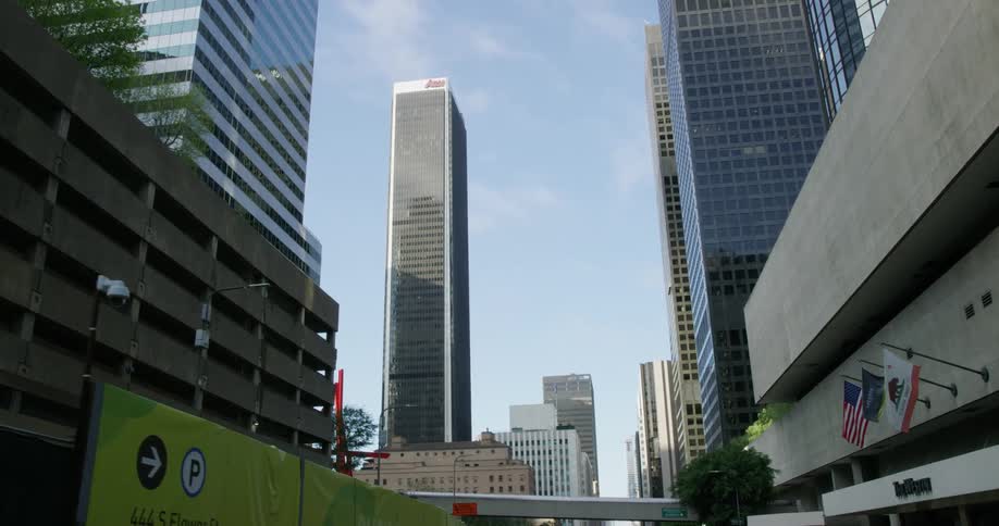 Flags on poles wave in the breeze and sunlight reflects off skyscraper windows and facade in a city on a sunny day