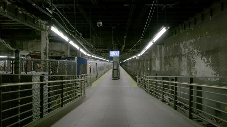 A subway train parked at an empty platform with door light flashing