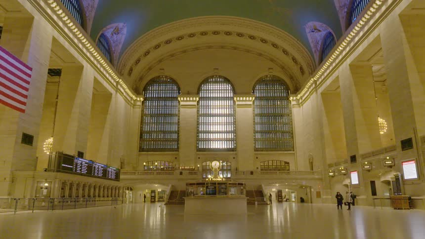Several people stand in an empty train station