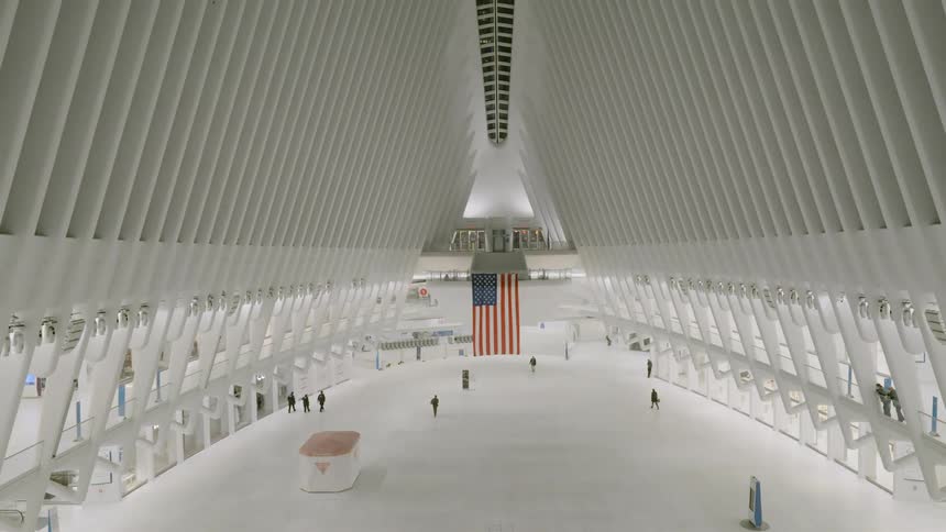 People in business attire walk through a large building with an arched ceiling