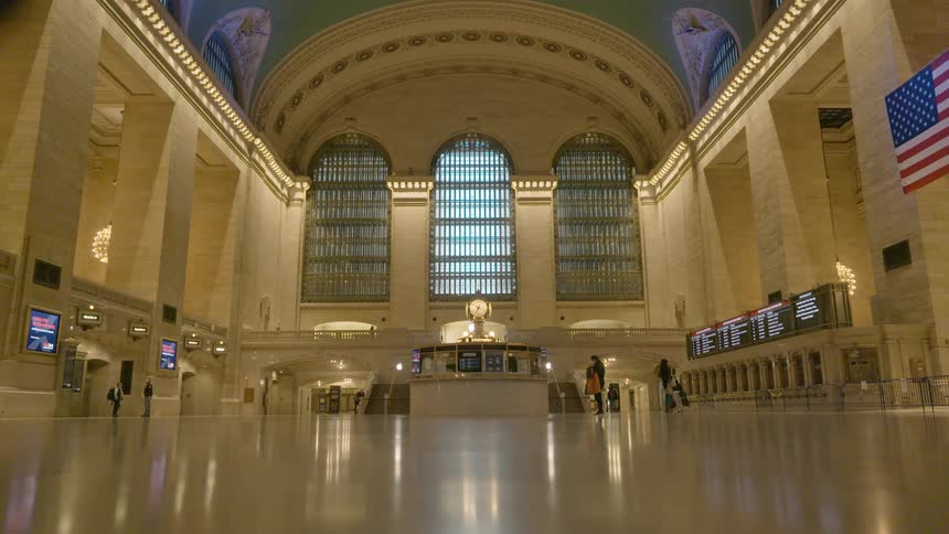 A few people walk in an empty train station