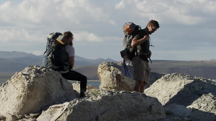 Two men with backpacks walk up rocks