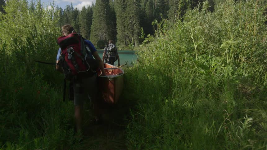 Two people are carrying a boat to the water ahead