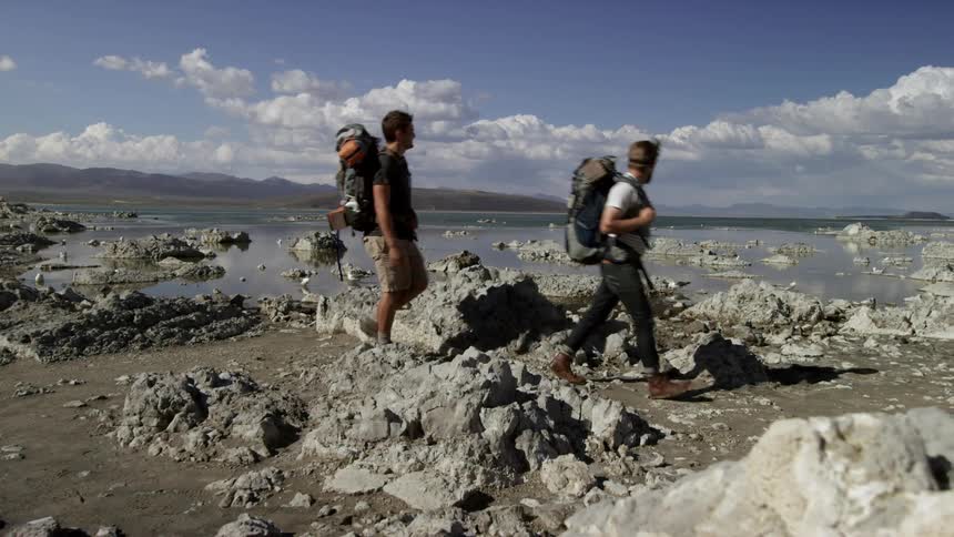 Two men walk across a tidal flat