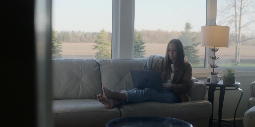 A woman sitting on a sofa using a laptop in her lap