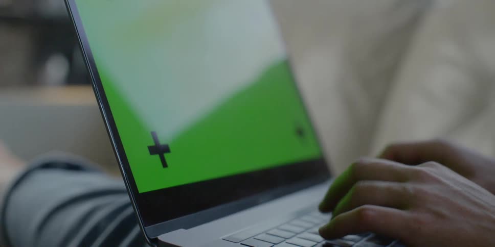 A person lies on a couch and uses a laptop