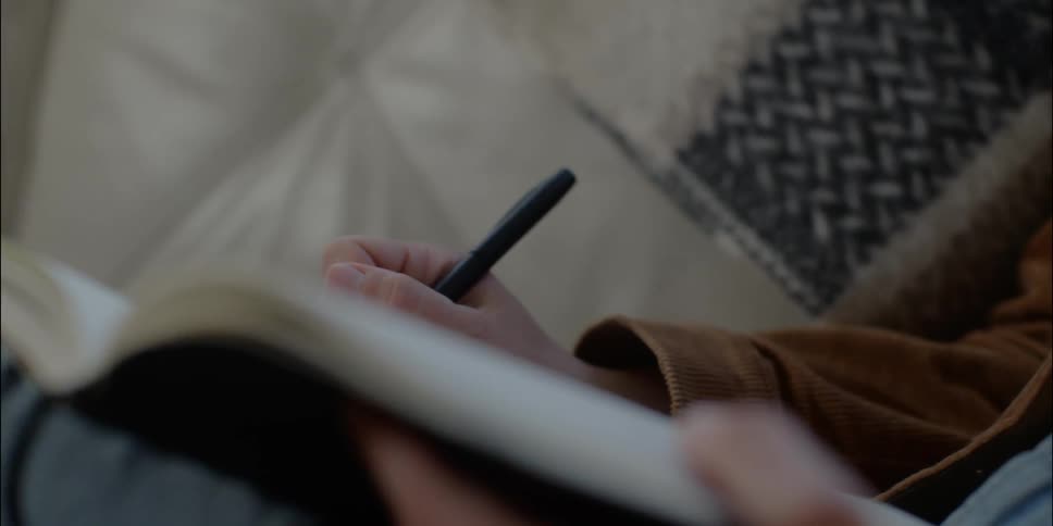 Person lies down writing in journal
