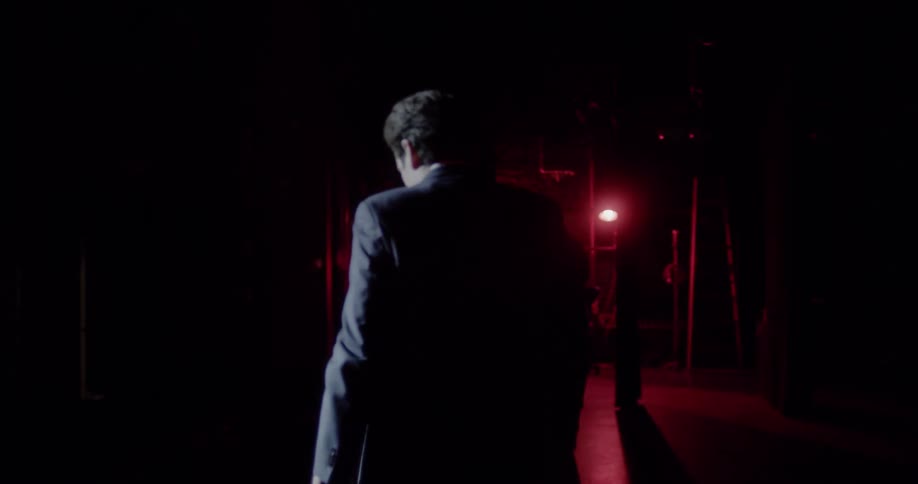 A man is told to go on stage and stands in front of an empty auditorium