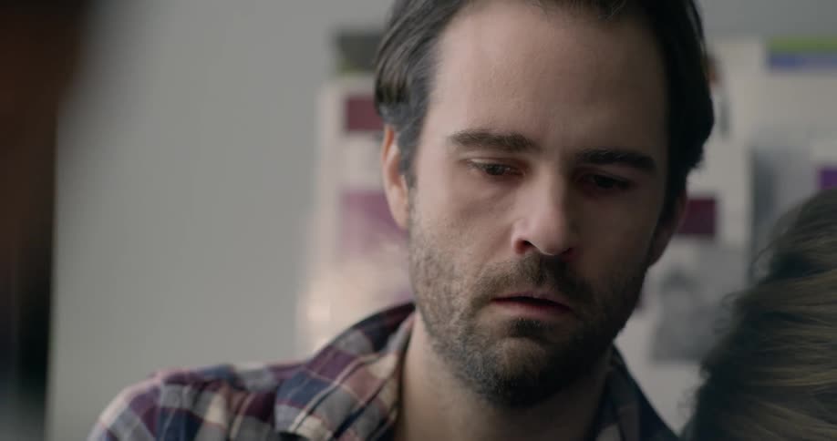 A man and woman sit in front of a doctor and cry as they appear to receive bad news