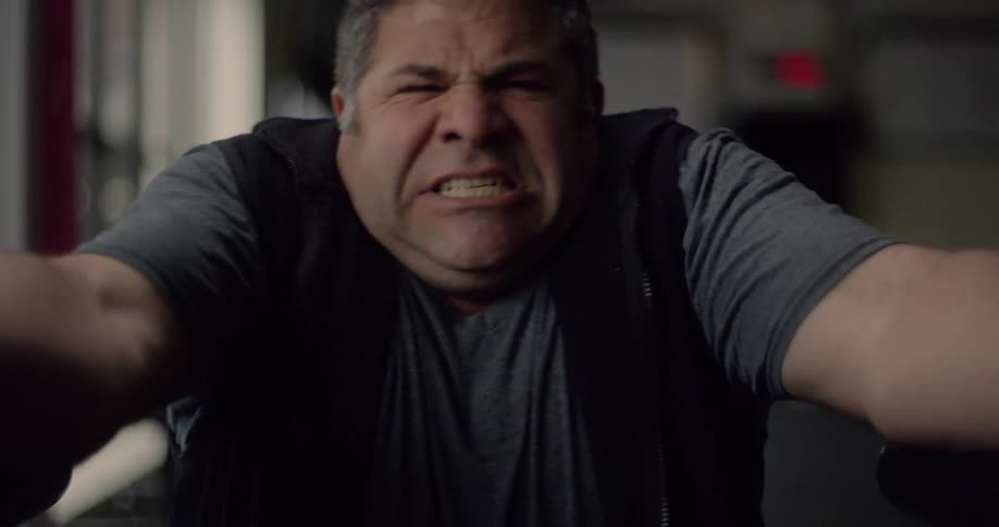 A man grimaces in determination and he grabs parallel bars and tries to stand up