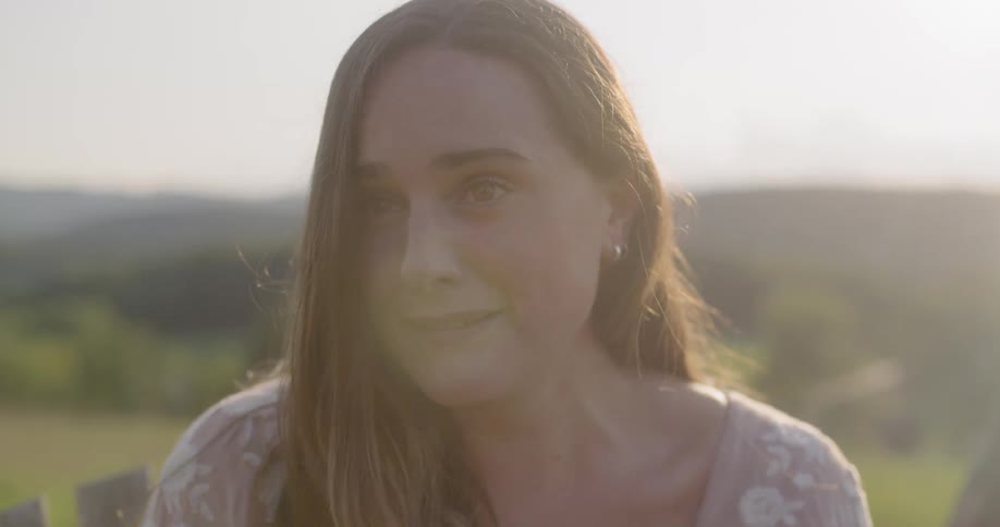 A woman is sitting outdoors at dusk