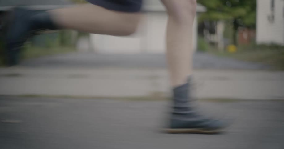 A young girl runs down a neighborhood street while pulling a suitcase behind her