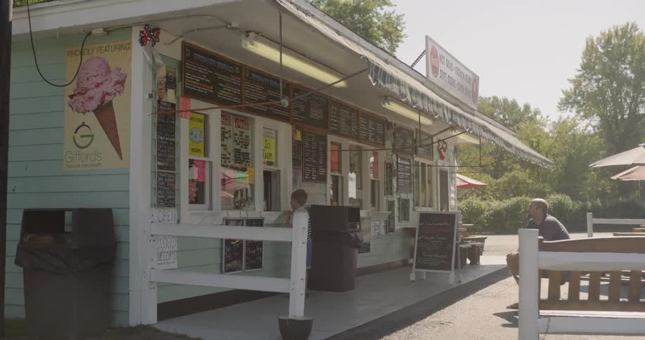 A boy orders outside an ice cream shop as his father watches