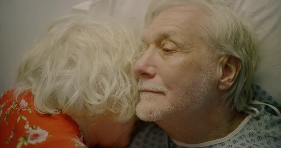 An elderly man and woman lay together