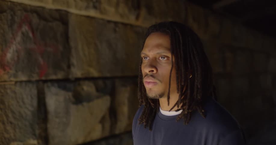 Man stands in brick walled tunnel breathing deeply and looking forward