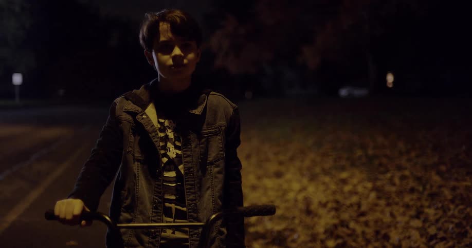 A boy sits on his bike in the dark