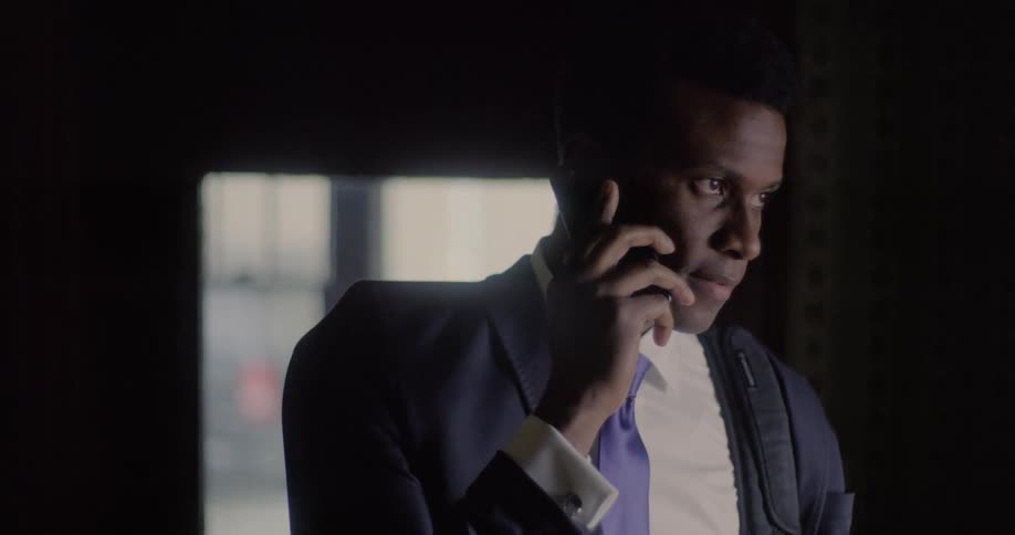 A man holding a phone to his ear rolls his eyes as he listens